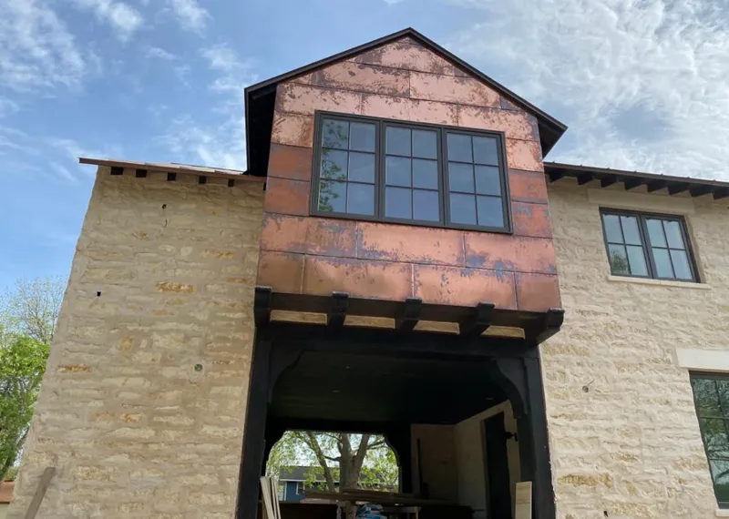 Copper metal panel facade on a stone building for Roof Repair in Graham